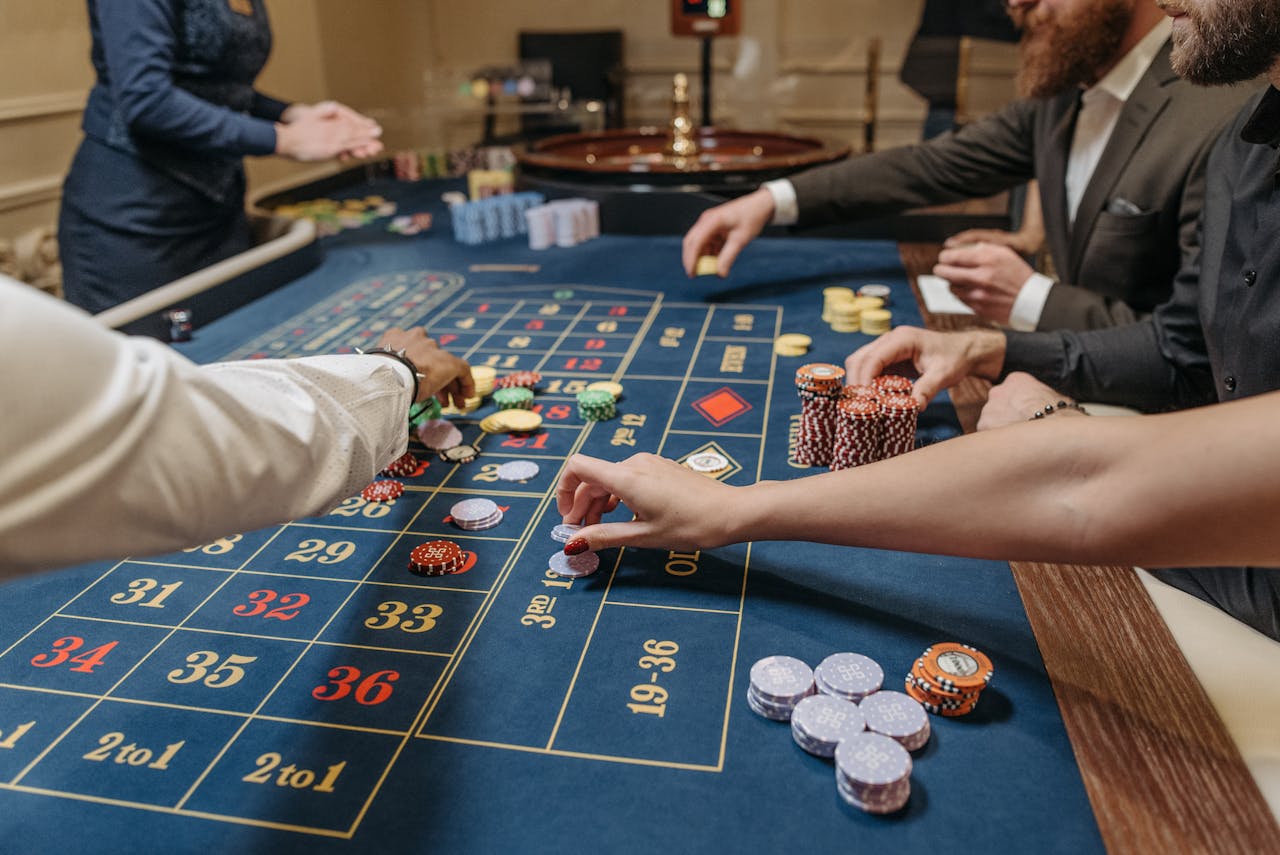 A lively casino scene with players placing bets and handling gaming chips on a roulette table.